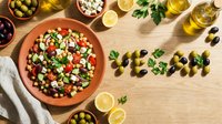 Fresh vegan chickpea salad with feta, tomatoes, olives on wooden table, word vegan made of olives, healthy Mediterranean diet concept.