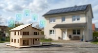 Wooden house model with smart home technology icons and solar panel house in background representing sustainable energy and modern living solutions.