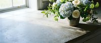Fresh spring flower arrangement with white roses and blue hydrangeas in rustic vase on wooden table near window for home decor and interior design projects.
