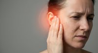 Middle-aged Caucasian woman experiencing severe ear pain touching inflamed ear with hand showing symptoms of infection or hearing problems.