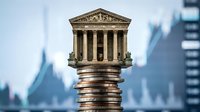 Classical courthouse building balanced on stack of coins representing legal costs, justice system expenses, and financial burden of litigation.