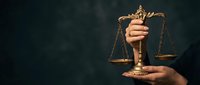 Hands holding golden scales of justice against dark background symbolizing law, legal system, fairness and judicial balance for legal services.