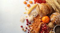 Fresh baked bread, pumpkin, cranberries, nuts and grains on white background with copy space. Autumn harvest composition for bakery or healthy eating.