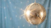 Shiny disco ball reflecting light with sparkling effects against soft blue background for party and celebration events.
