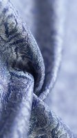 Close-up of blue denim fabric with herringbone weave texture and natural folds, showcasing textile detail for fashion, apparel design, and material reference.