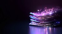 Glowing neon waves with sparkling particles create magical light effect on dark background. Abstract digital art design with luminous purple and blue streaks.