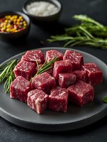 Raw beef tenderloin cut into cubes with fresh rosemary sprigs on dark plate, seasoning and spices in bowls, moody food photography styling.