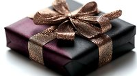 Elegant gift box wrapped in purple and black paper with shimmering copper ribbon bow on white background.