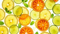 Sliced citrus fruits including lemons, limes, and oranges arranged with fresh green leaves on white background for food and beverage design.