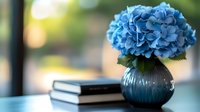 Blue hydrangea flowers in decorative vase with books on table creating elegant home decor arrangement for interior design and lifestyle photography.