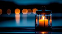 Glowing candle lantern at dusk with bokeh lights reflecting on water surface creates peaceful atmospheric mood. Perfect for meditation and wellness designs.