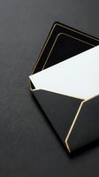 Elegant black envelope with gold trim and white card on dark background for luxury stationery, wedding invitations, and premium correspondence designs.