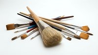 Assorted artist brushes with natural bristles and wooden handles arranged on white background, ready for painting, drawing, and design projects.