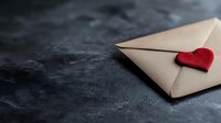 Romantic letter envelope with red heart decoration on dark textured background. Love message concept with minimalist composition and moody atmosphere.
