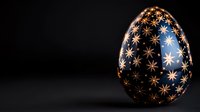 Decorative Easter egg with golden star pattern on dark blue background, illuminated against black backdrop. Elegant holiday design element.