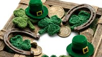 St. Patrick's Day festive composition with green leprechaun hats, knitted shamrocks, horseshoes and golden coins on rustic wooden background for holiday celebrations.