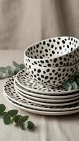 Stacked ceramic dinnerware set with black polka dot pattern on white glaze, featuring bowls and plates for dining and tableware styling.