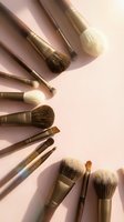 Professional makeup brushes with golden ferrules arranged on soft pink background for beauty and cosmetics applications.