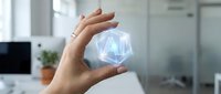 Hands protecting glowing AI artificial intelligence hologram in modern office environment for technology innovation and digital transformation concepts.