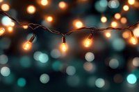 Glowing string lights with warm yellow bulbs against blurred teal bokeh background create magical festive atmosphere for holiday and party decoration.