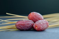 Fresh red dates with wheat stalks on dark background for healthy eating and natural nutrition concepts.