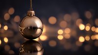 Elegant gold Christmas ornament with reflection against dark background with warm bokeh lights for holiday decoration.