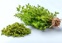 Fresh thyme herb bundle with twine and loose dried leaves on white background for cooking, food photography, and culinary use.