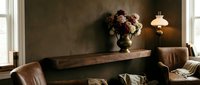 Elegant living room interior with brown leather sofa, wooden console table, fresh flower arrangement, and warm pendant lighting for home decor design.