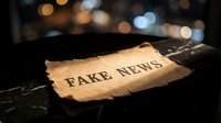 Torn paper with fake news text on dark surface with blurred city lights bokeh background representing misinformation and media manipulation concepts.