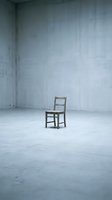 Wooden chair sitting alone in empty concrete industrial space with bare walls, conveying isolation, abandonment, and minimalist aesthetics for conceptual design projects.