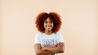 Confident African American woman with curly hair wearing motivational shirt against neutral background for empowerment and personal development content.