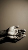 Open cupped hands in sepia tone reaching out in gesture of giving, receiving or prayer against neutral background for spiritual and charity concepts.