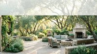 Luxury outdoor patio with stone fireplace, comfortable seating and mature trees creating elegant backyard living space for entertaining guests.