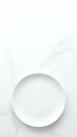 Empty white ceramic plate on marble surface with subtle veining, overhead view. Minimalist tableware composition for dining, restaurant, and food styling projects.
