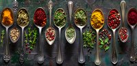 Colorful dried herbs and spices in vintage silver spoons arranged on dark rustic background with fresh herbs, turmeric, paprika and peppercorns. Food seasoning concept.