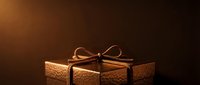 Luxury gift box with textured golden surface and decorative rope bow on warm brown background for holiday and celebration designs.
