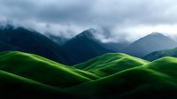 Dramatic mountain landscape with vibrant green rolling hills in foreground contrasting against dark stormy peaks shrouded in low-lying clouds, creating moody atmospheric scenery.