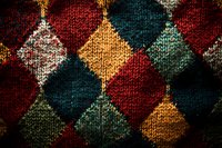 Vintage argyle knit pattern in dark red, teal, and mustard yellow creates classic diamond shapes with textured wool fabric detail, suitable for fashion backgrounds.