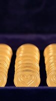 Stacked gold coins with heart symbol engraved on surface against dark background, representing wealth, savings, investment and financial security for business concepts.