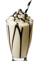 Creamy vanilla milkshake with chocolate syrup drizzle, topped with whipped cream and striped straw on white background for menu or advertising.