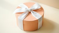 Round peach gift box with white satin ribbon bow on neutral background for special occasions and celebrations.
