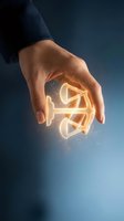 Businessman holding glowing light bulb with golden energy particles in palm against blue background, representing innovation, ideas, and creative business solutions.