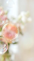 Delicate soap bubbles floating in soft pastel light with dreamy bokeh background creating magical atmosphere for spring and summer concepts.
