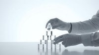 Man in gray gloves pushing over stacked silver blocks in domino effect, representing business failure, risk management, and financial collapse for corporate concepts.