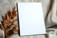 Blank white vertical card mockup with dried brown autumn oak leaves on neutral beige linen fabric background. Minimal flat lay composition for branding.