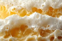 Extreme close-up of fresh honeycomb texture showing natural golden honey cells and white wax structure in macro photography, revealing intricate organic patterns.