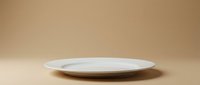 Empty white ceramic plate on neutral beige background, suitable for food photography, product mockups, and culinary design projects.