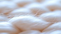 Soft white fluffy fur texture in macro photography showing delicate individual strands and gentle curves creating an abstract natural pattern background.