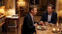 Two middle-aged men of Caucasian ethnicity engaged in conversation over dinner in an upscale residential setting, suitable for business, lifestyle, and hospitality concepts.