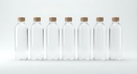 Seven clear glass bottles with cork stoppers arranged in row on white background, empty containers for storage, crafts, or decorative purposes.